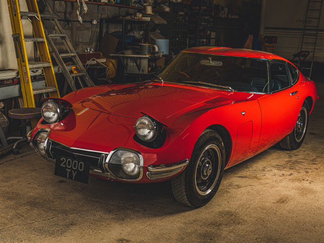 The 2000GT sits static in a garage with the pop-up headlights up.