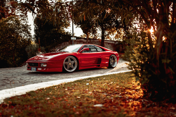 Arianna's stanced Ferrari 348 standing static on a cobbled path in Italy.